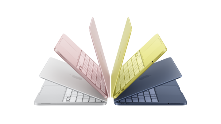 Five partially open macbook neo laptops arranged in a circular fan shape, displayed in silver, pink, yellow, and dark blue colors.